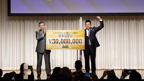 Mr. Takada Masato (à droite) se faisant remettre le chèque de 30 millions de yens par le présentateur et mangaka, Hirokane Kenshi